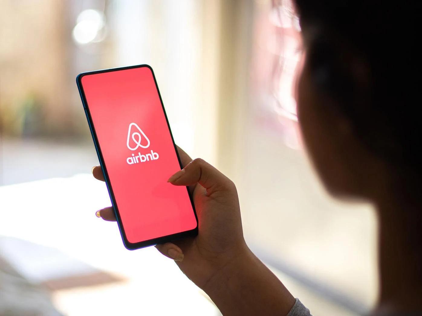 Pessoa segurando um celular com o aplicativo do Airbnb aberto na tela