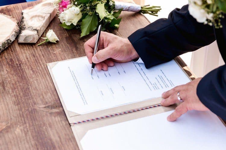 Alianças de casamento sobre documento representando o pacto antenupcial